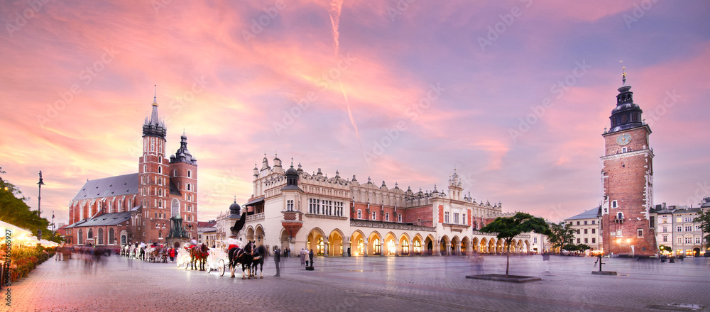 Fototapeta premium Panorama of St Mary's Basilica (Mariacki Church) and The Main Market and tower in the Old Town of Krakow, Poland illuminated at sunset