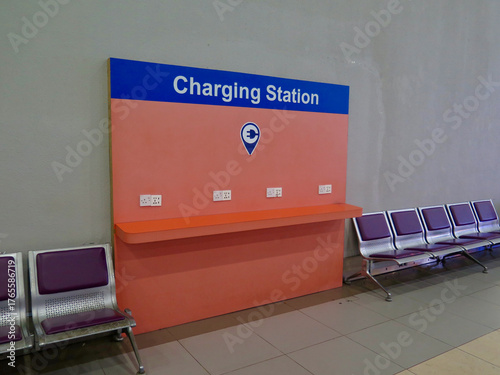 Bright charging station with multiple power outlets in a modern airport waiting area. Empty seats and clean design highlight comfort and convenience for travelers.