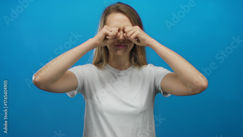 Schilderij op canvas Young caucasian woman in white shirt rubbing eyes with surprise against isolated blue background wall