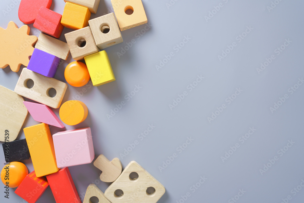 Obraz premium Colorful wooden toy blocks in various shapes on gray background, concept for childhood learning, creativity, education, Montessori play, and preschool development.