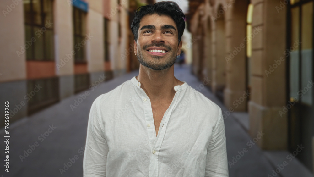 Obraz premium Man smiling showing teeth while looking up on historic sunlit street; optimism curiosity adventure inspiration.