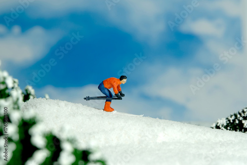 Miniature people toy figure photography. Winter sport. A male downhill ski racer slides down from the top of the hill.