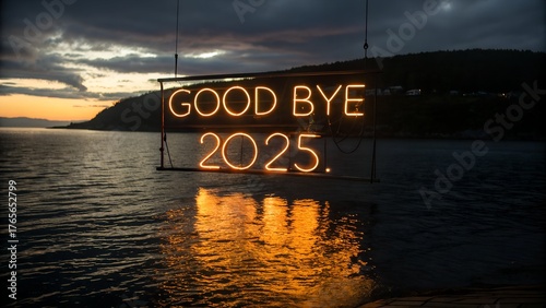 Neon sign saying good bye 2025 illuminated over dark water at sunset with reflection silhouette