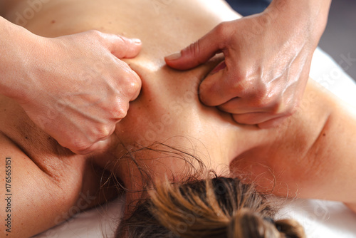 Foto Therapist applying deep tissue massage on female client is upper back using thum