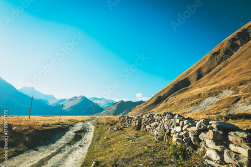 Vászonkép A winding dirt road and traditional stone fence in Truso Valley, Georgia, leadin