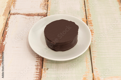 Dark chocolate alfajores filled with creamy ganache and dipped in semisweet chocolate, decorated with chopped walnuts and edible gold foil