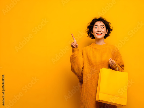 woman holding paper shopping bag and pointing upward