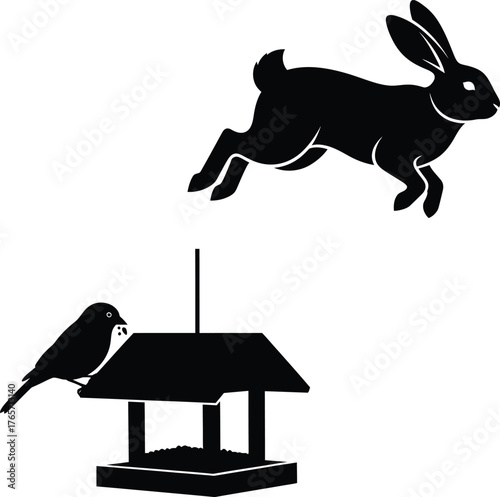 Silhouette of a jumping rabbit above a bird feeder with a small bird eating seeds