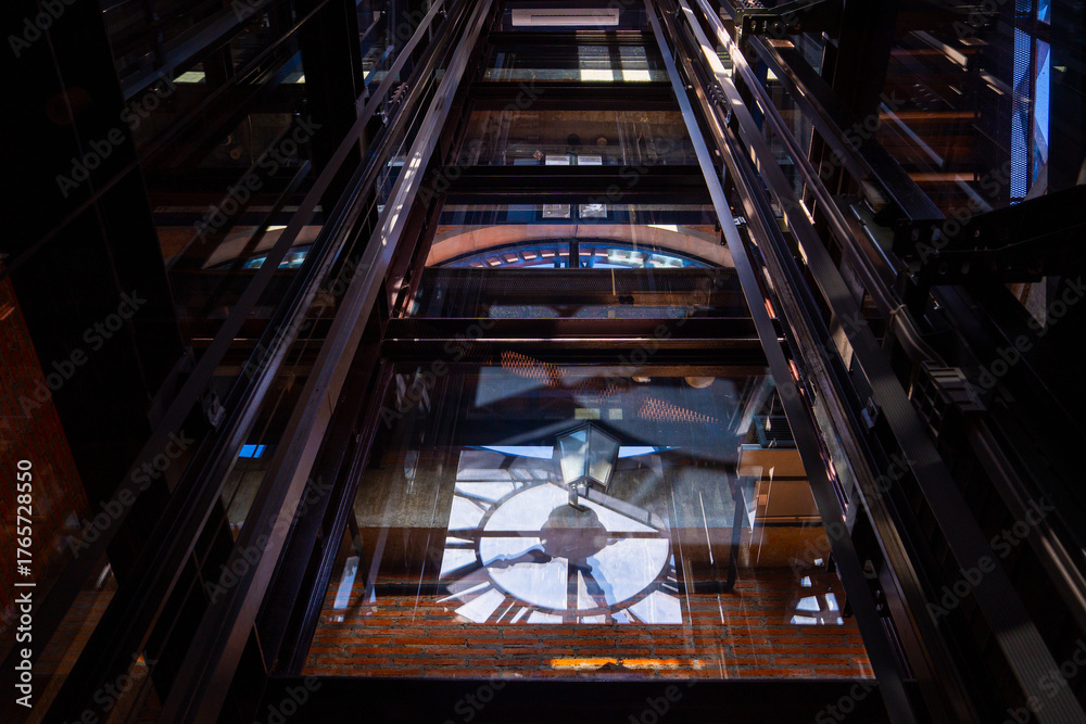 Obraz premium View of clock tower interior with intricate metal and glass structures reflecting light. architectural design creates dramatic Clock tower