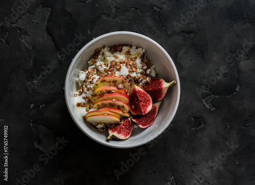 Delicious healthy breakfast - cottage cheese with Greek yogurt, granola, apple, figs and honey on a dark background, top view