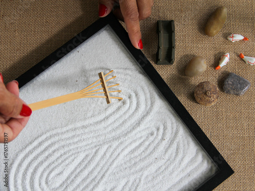 Flat lay overhead of woman meditating with a zen garden helping her to relax and keep her mind healthy for mental heath concept. 