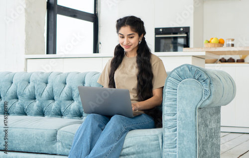 Indian woman student studying at home while sitting on sofa. Distance learning, communication, working idea.