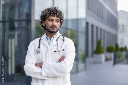 Canvas Print Close-up photo of a serious young Indian male doctor in a white uniform and with