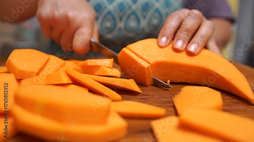 Slicing vegetables pumpkin. Female hands cut carrot on a wooden cutting board. Cooking in the kitchen. Food preparation. Close-up.