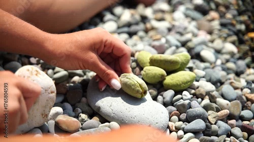 Beach Stones Hands: Hands arrange beach stones to build a stack during sunny day for vacation fun.