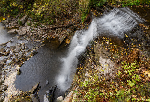 A picturesque view of Smokey Hollow Falls in Hamilton, Ontario, surrounded by vibrant autumn foliage and tranquil wilderness.
