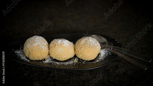 homemade curd cheese dumplings with powder sugar, a austrian cuisine, served on a black plate