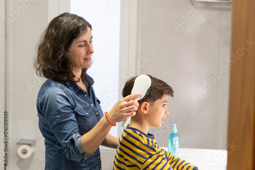 Mother combing her 10-year-old son's hair in the bathroom before school