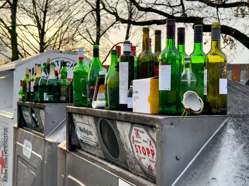 Viele leere Flaschen stehen auf überfüllten Altglas Containern