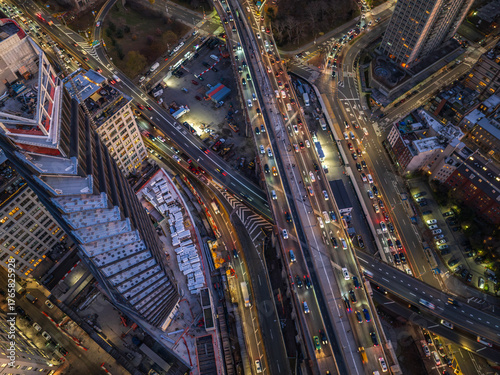 Aerial view of the bustling cityscape, where roads converge and buildings stand tall, illuminated by the warm glow of city lights, Brooklyn Bridge, New York, United States.