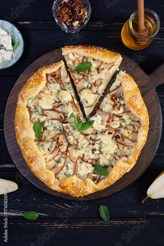 Homemade pear brie galette on wooden board, golden crust, melted cheese, honey glaze. Sliced galette with pear and bri cheese