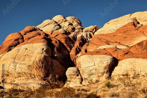 Vibrant Red Sandstone Peaks Rise Majestically Against Azure Skies in Red Rock Canyon's Ancient Desert Embrace, Nevada