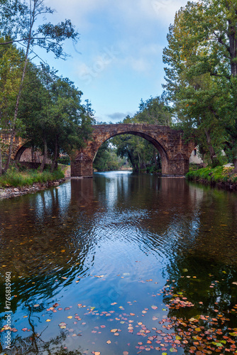 A historic stone arch bridge spans a calm, clear river