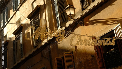 Merry Christmas golden glitter sign stretches across the street in the historic old town of Rome,Italy. .Post card concept.High quality photo