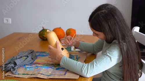 Female child painting pumpking during fall season for Halloween event - Holiday, childhood and autumn lifestyle concept