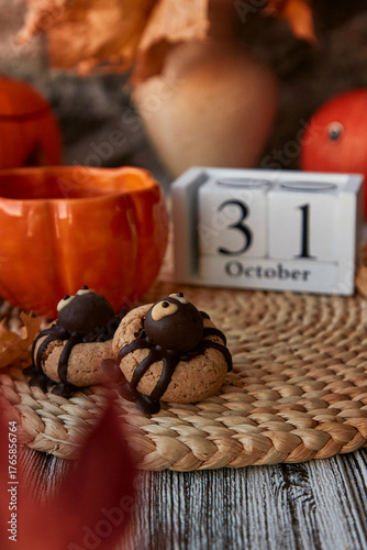 Aesthetics autumn Halloween cookies in shape of spider and cup of tea in shape of pumpkin near 31 of October on calendar