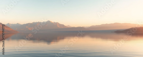 Tranquil morning landscape with serene lake and distant mountains at sunrise