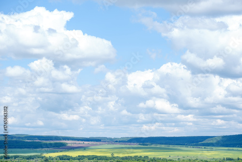 fields and trees against the backdrop of a sky with clouds