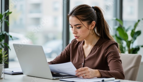Focused young professional woman working intently in modern office document review bright environment close-up perspective