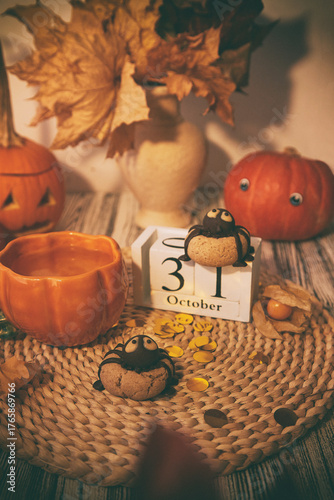 Traditional autumn Halloween cookies in shape of spider and cup of tea among pumpkins. 31 of October on calendar