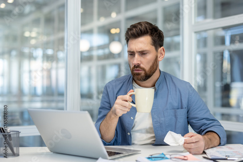 Businessman looking concerned while holding a coffee mug and crumpled paper, feeling stressed from work and experiencing burnout in a modern office environment