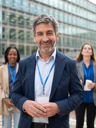Professional businessman smiling with lanyard at a conference leading teamwork