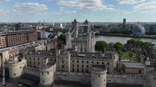 Cinematic 4K drone footage of the Tower of London and Tower Bridge, showcasing the historic fortress, River Thames, and the vibrant London skyline under clear summer light.