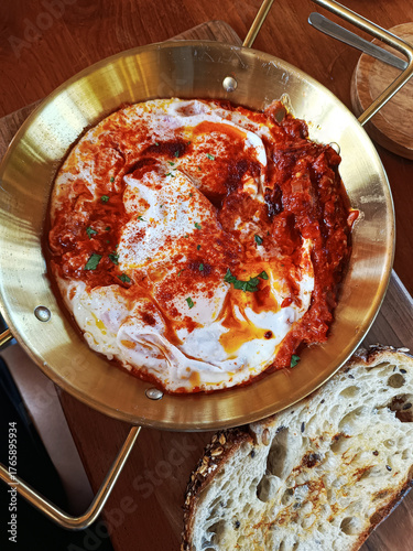 Delicious shakshuka with spicy tomato sauce, green onions and spices