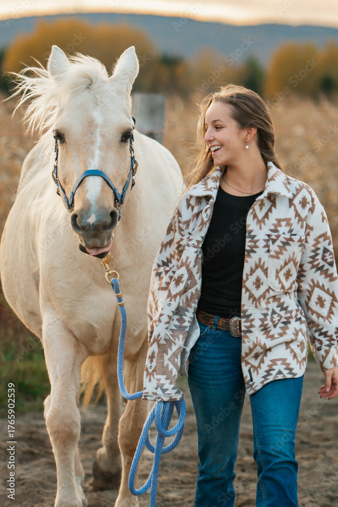 Fototapeta premium Young woman having great time with a horse in field on autumn season. sunset hour