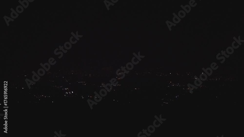 The night view of Bandung city lights seen from the top of Mount Pangradinan, showing a stunning cityscape under the dark sky.