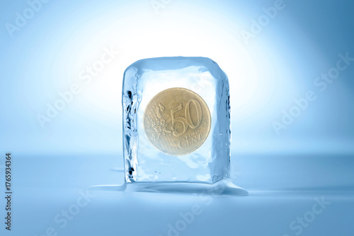 Fifty euro cent coin in ice cube on light blue background. Frozen money