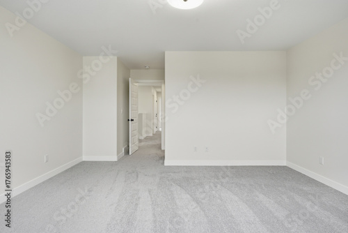 Large, empty room with a white door and a white wall