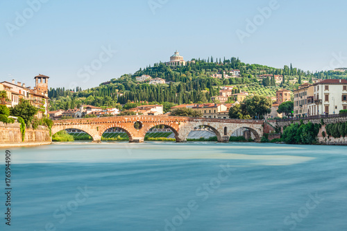Die römische Ponte Pietra über dem Fluß Etsch in der Altstadt von Verona vor mediterraner Landschaft in der Morgensonne, Venetien, Italien
