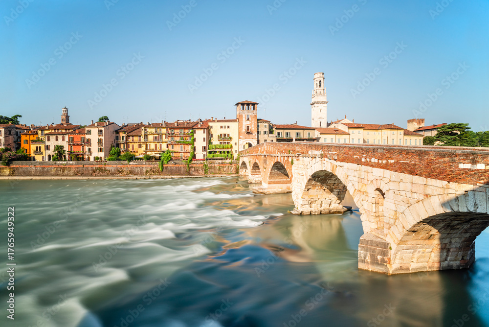 Obraz premium Die römische Ponte Pietra über dem Fluß Etsch mit dem Panorama der Altstadt von Verona in der Morgensonne, Venetien, Italien