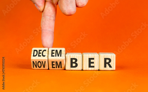 Symbol for the change from November to December. Businessman turns wooden cubes and changes the word November to December. Beautiful orange background. Happy December concept. Copy space.