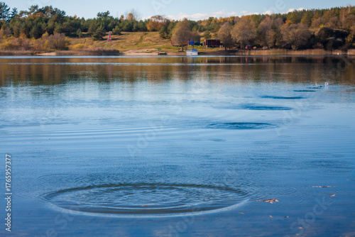 Fotografie Ripples and splashes on water surface from skipping stones