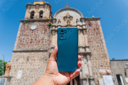 Hand holding smartphone capturing historic church in tequila, mexico