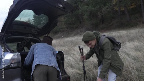 Couple unpacking car trunk for hiking trip in nature