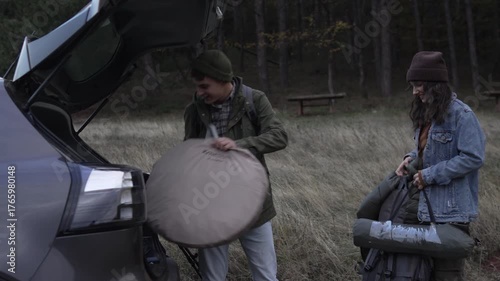 Couple unpacking car trunk for hiking trip in nature