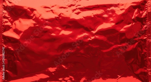 Crumpled red metallic foil texture background shiny surface abstract